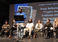 A poet stands at a podium to recite a poem reflecting on HNOC's Captive State exhibition